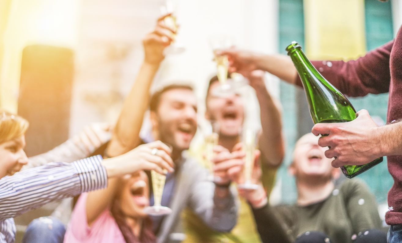 Several people celebrating with alcoholic drinks in their hands